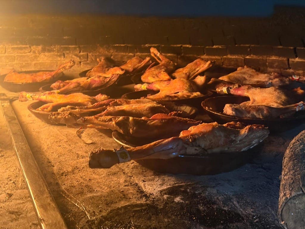 Lechazo asado en cazuelas de barro en horno de leña