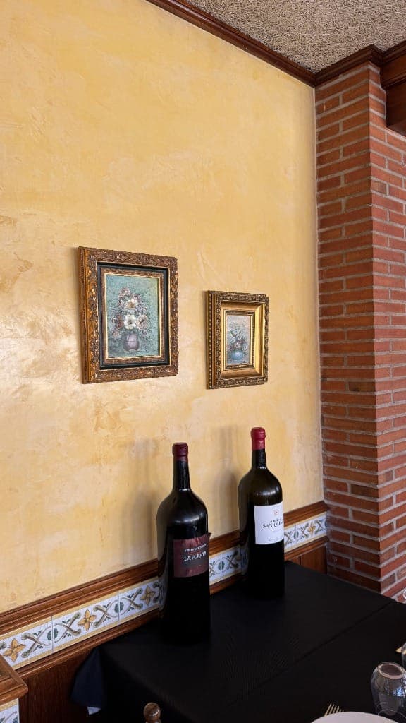 Rincón del comedor con botellas magnum y cuadros dorados