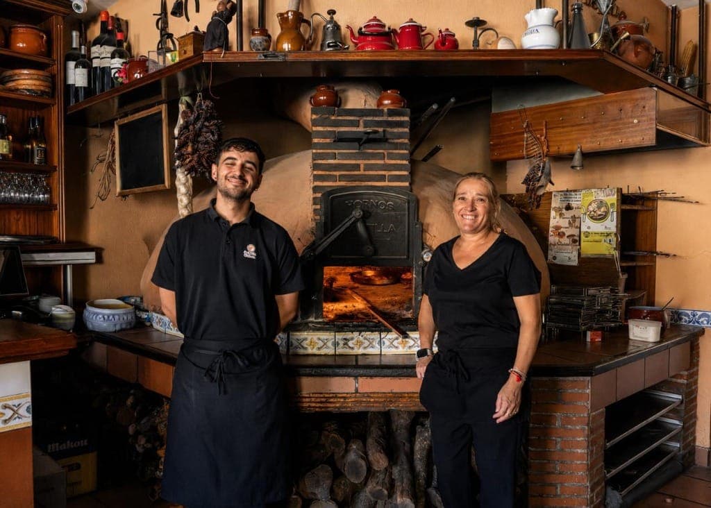 Merche y Miguel, propietarios de Asador La Antigua frente al horno de leña en Quintanadueñas, Burgos